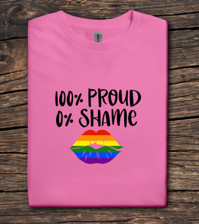 Pink t-shirt with '100% Proud 0% Shame' text and rainbow flag on a wooden surface