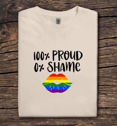 Beige t-shirt with '100% Proud 0% Shame' text and rainbow lips design on a wooden surface