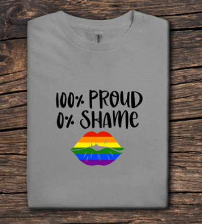 Gray t-shirt with '100% Proud 0% Shame' text and rainbow lips design on a wooden surface