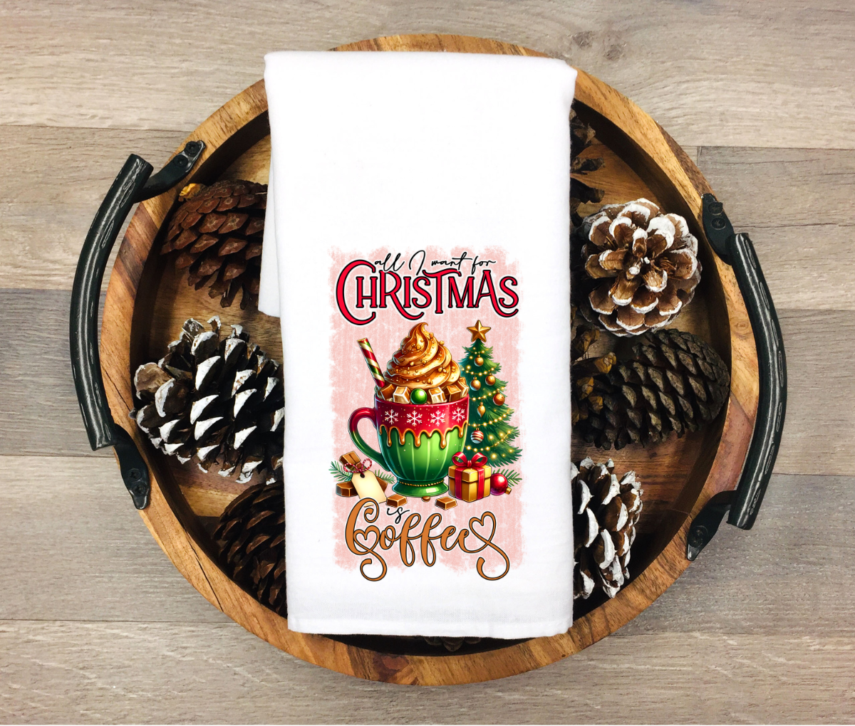 Decorative towel with Christmas design featuring a mug of hot chocolate and pinecones on a wooden tray.