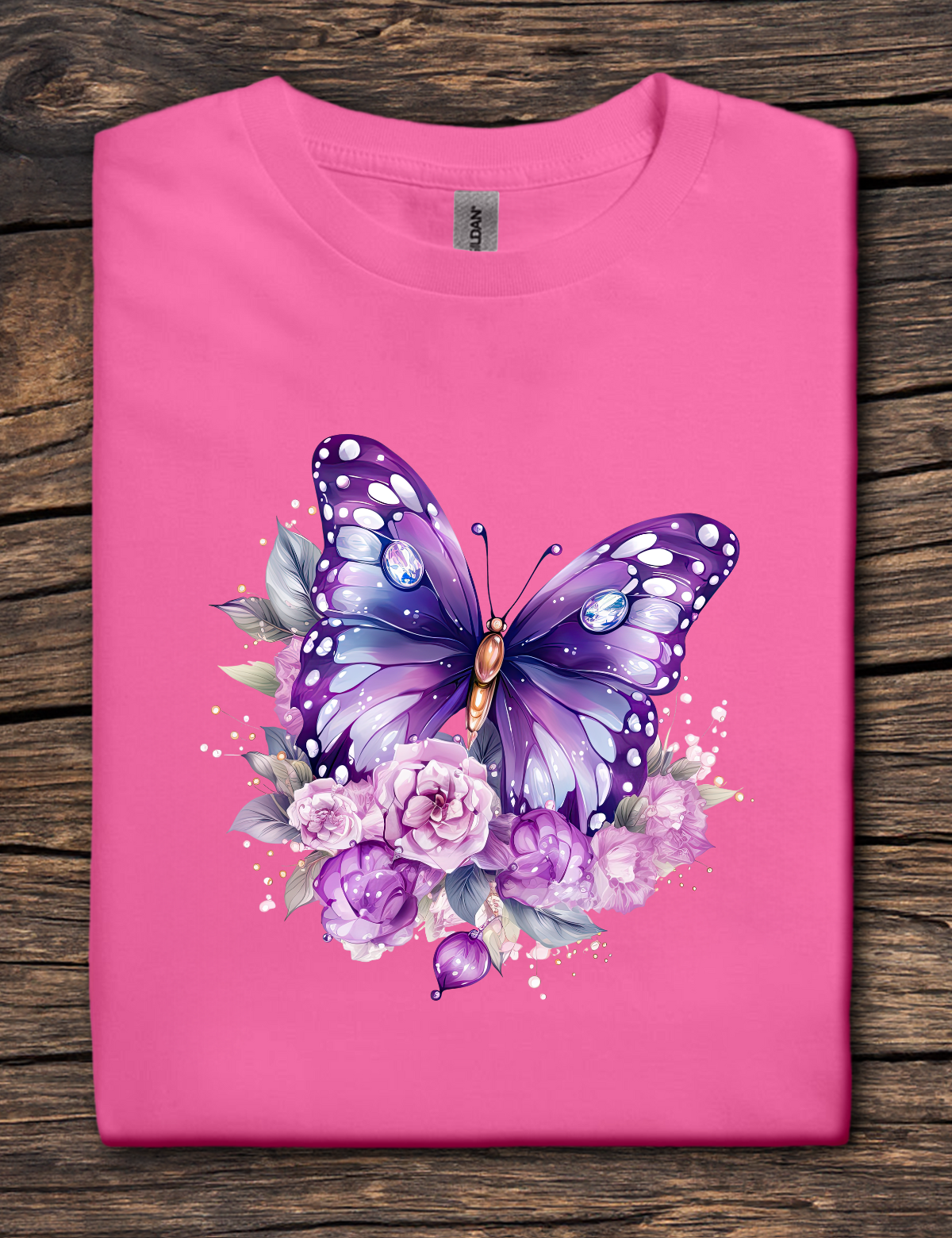 Pink t-shirt with a purple butterfly and floral design on a wooden surface