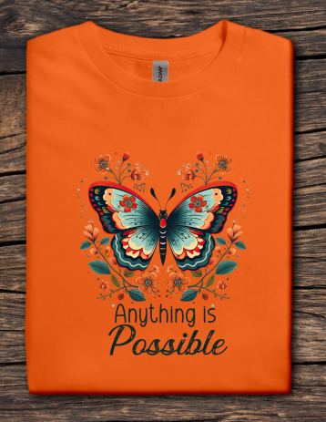 Orange t-shirt with a butterfly design and 'Anything is Possible' text on a wooden surface
