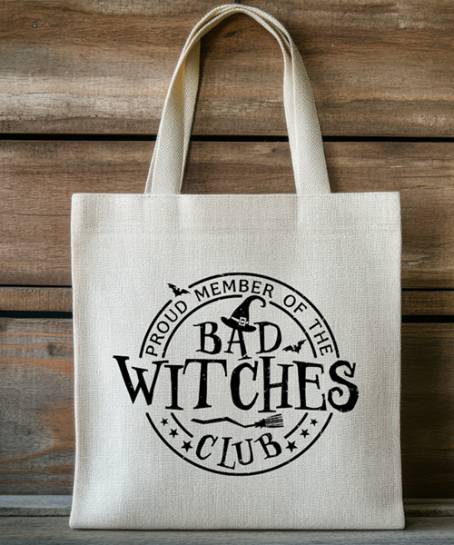 Natural canvas tote bag with black print reading “Proud Member of the Bad Witches Club” featuring a witch hat, broom, and stars.