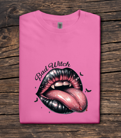 Pink t-shirt with a graphic of lips and 'Bad Witch' text on a wooden surface