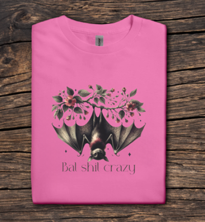 Pink t-shirt with a bat and floral design on a wooden surface