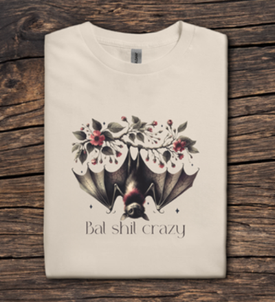 Beige t-shirt with a bat and floral design on a wooden surface