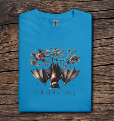 Blue t-shirt with a bat and floral design on a wooden surface