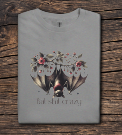 Gray t-shirt with a bat graphic and 'Bat shit crazy' text on a wooden surface