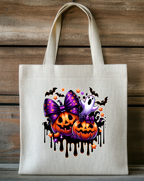 Tote bag with Halloween design featuring pumpkins, a purple bow, and ghosts on a wooden background.