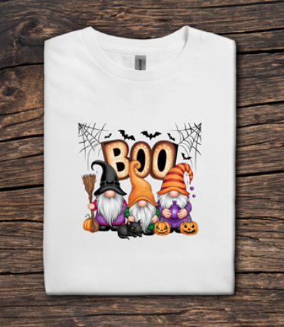 White t-shirt with Halloween-themed design featuring gnomes and 'BOO' text on a wooden surface.