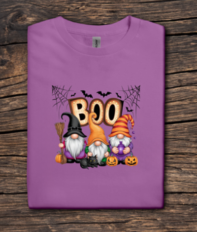 Purple t-shirt with Halloween-themed design featuring gnomes and 'BOO' text on a wooden surface.
