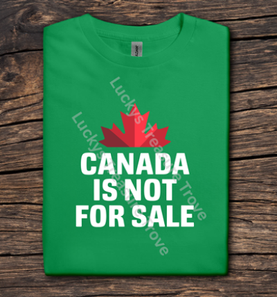 Green t-shirt with a red maple leaf and 'Canada is not for sale' text on a wooden surface