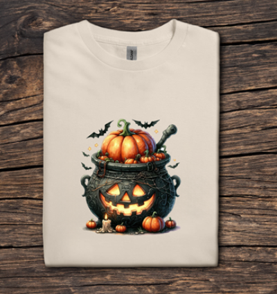 Folded t-shirt with Halloween-themed design featuring pumpkins and a cauldron on a wooden surface