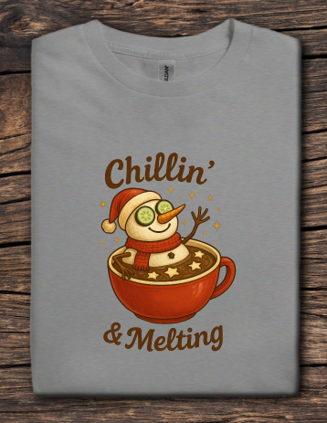 Gray t-shirt featuring a snowman relaxing in a mug of hot cocoa with the text “Chillin’ & Melting”.