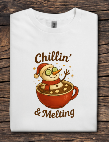 White t-shirt featuring a snowman relaxing in a mug of hot cocoa with the text “Chillin’ & Melting”.