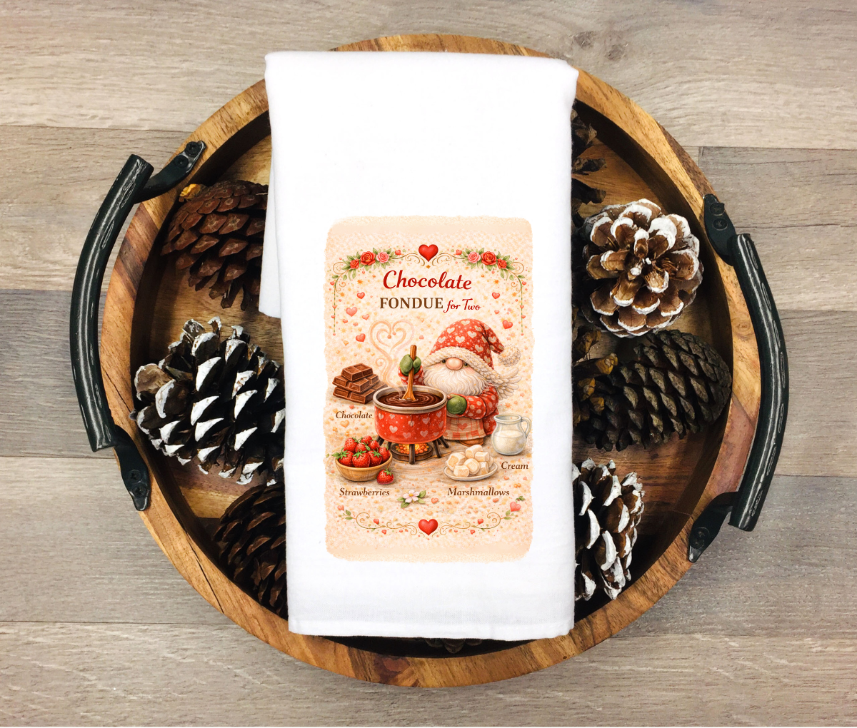 White kitchen towel featuring a Valentine gnome with a pot of chocolate fondue surrounded by strawberries, marshmallows, chocolate and cream with the words “Chocolate Fondue for Two”
