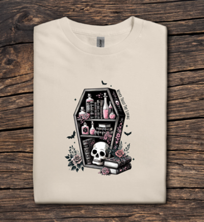 Beige t-shirt with a coffin design featuring bottles, a skull, and flowers on a wooden surface.
