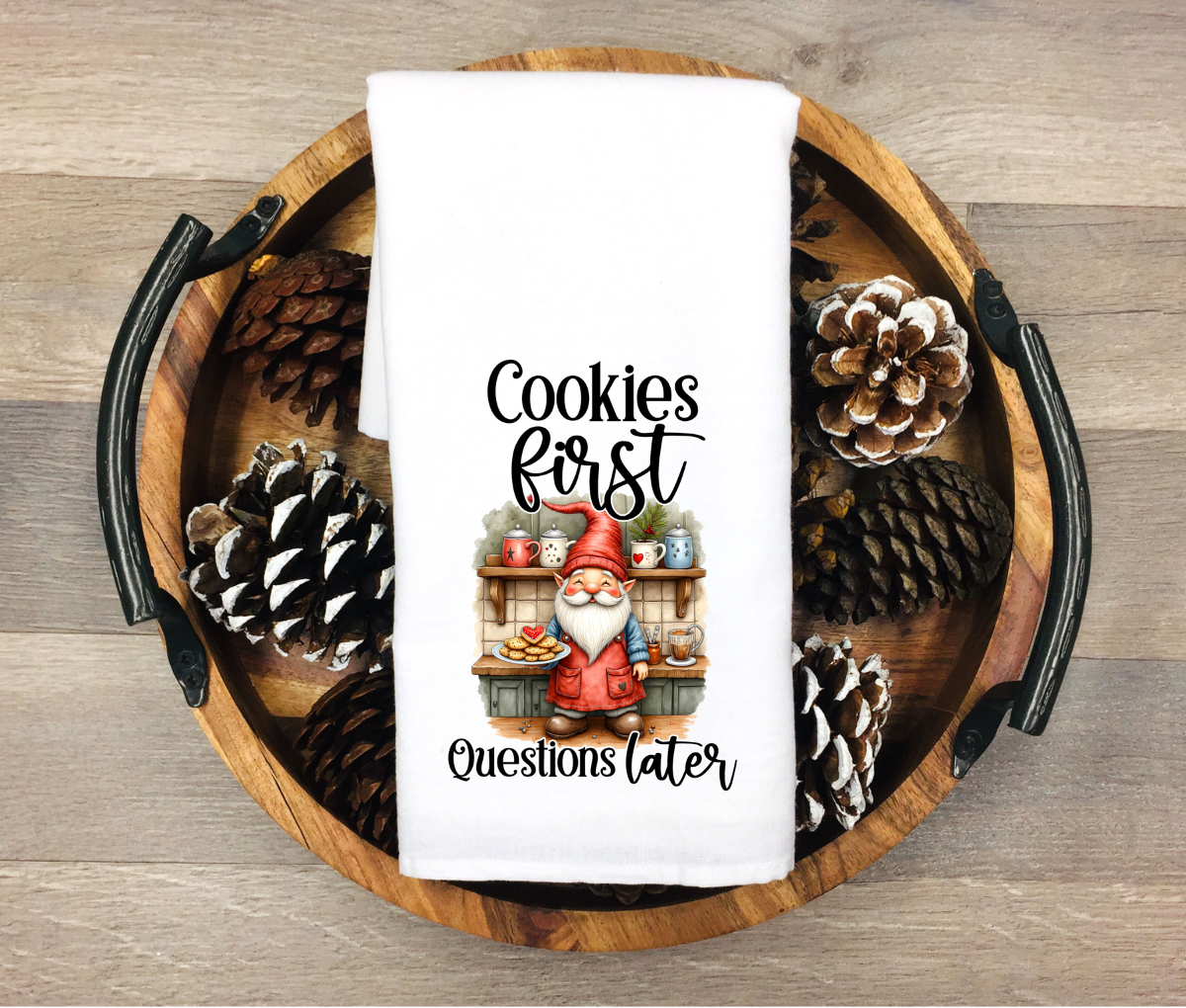 White kitchen towel featuring a baking gnome holding cookies in a farmhouse kitchen with the phrase “Cookies First Questions Later”