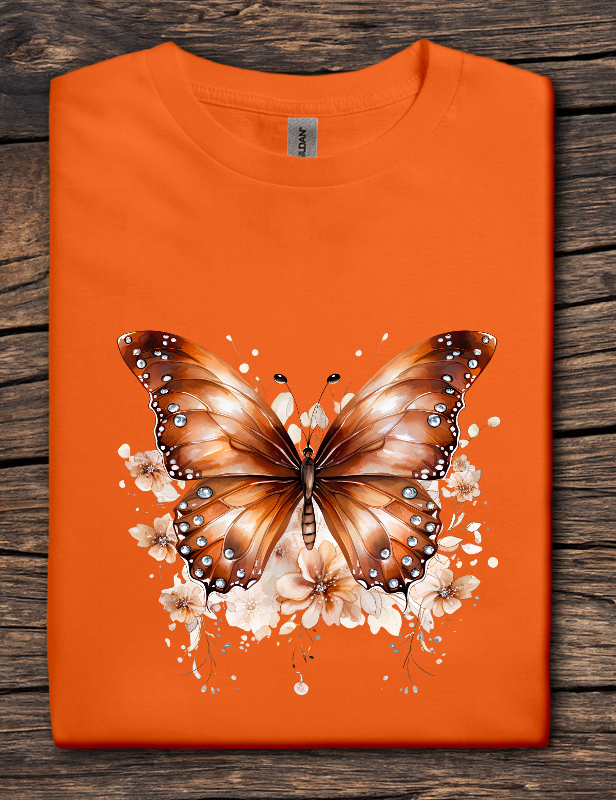 Orange t-shirt with copper-colored butterfly graphic surrounded by soft floral accents.