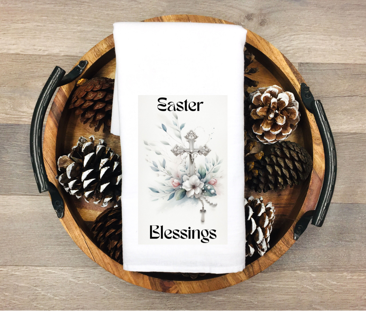 White kitchen towel featuring a decorative cross surrounded by flowers and greenery with the words “Easter Blessings”