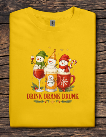 Yellow t-shirt with Christmas-themed design featuring snowmen and text on a wooden surface
