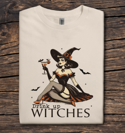 T-shirt with a witch design and 'Drink up Witches' text on a wooden surface
