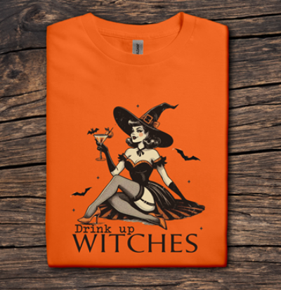 Orange t-shirt with a witch graphic and 'Drink up Witches' text on a wooden surface