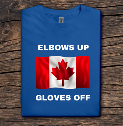 Blue t-shirt with Canadian flag and text 'ELBOWS UP GLOVES OFF' on a wooden surface