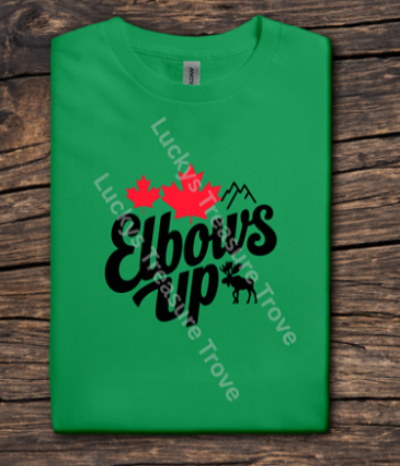 Green t-shirt with 'Elbows Up' design on a wooden surface