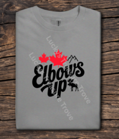 Gray t-shirt with 'Elbows Up' and maple leaf design on a wooden surface