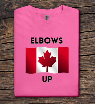 Pink t-shirt with Canadian flag and 'ELBOWS UP' text on a wooden surface
