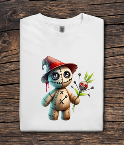 White t-shirt with a cartoon voodoo doll design on a wooden surface