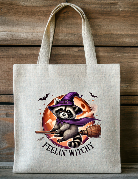 Canvas tote bag with cute raccoon dressed as a witch holding a broom and feelin witchy text