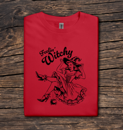 Red t-shirt with 'Feelin' Witchy' design on a wooden surface