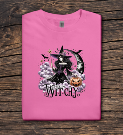 Pink t-shirt with a witch graphic and 'Witchy' text on a wooden surface