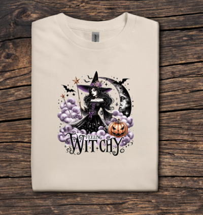 Beige t-shirt with a witch graphic and 'Witchy' text on a wooden surface