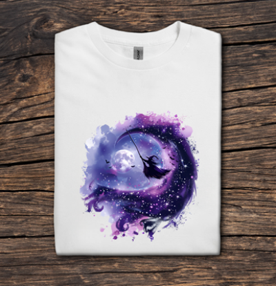 White t-shirt with a purple and blue design of a crescent moon and fairy on a wooden surface