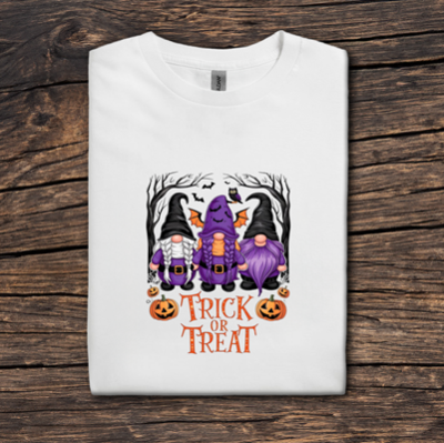 White t-shirt with Halloween-themed design featuring purple gnomes and pumpkins on a wooden surface.