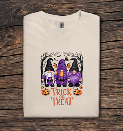 Beige t-shirt with Halloween-themed design featuring gnomes and 'Trick or Treat' text on a wooden surface.