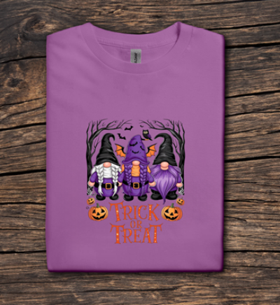 Purple t-shirt with Halloween-themed design featuring gnomes and pumpkins on a wooden surface.