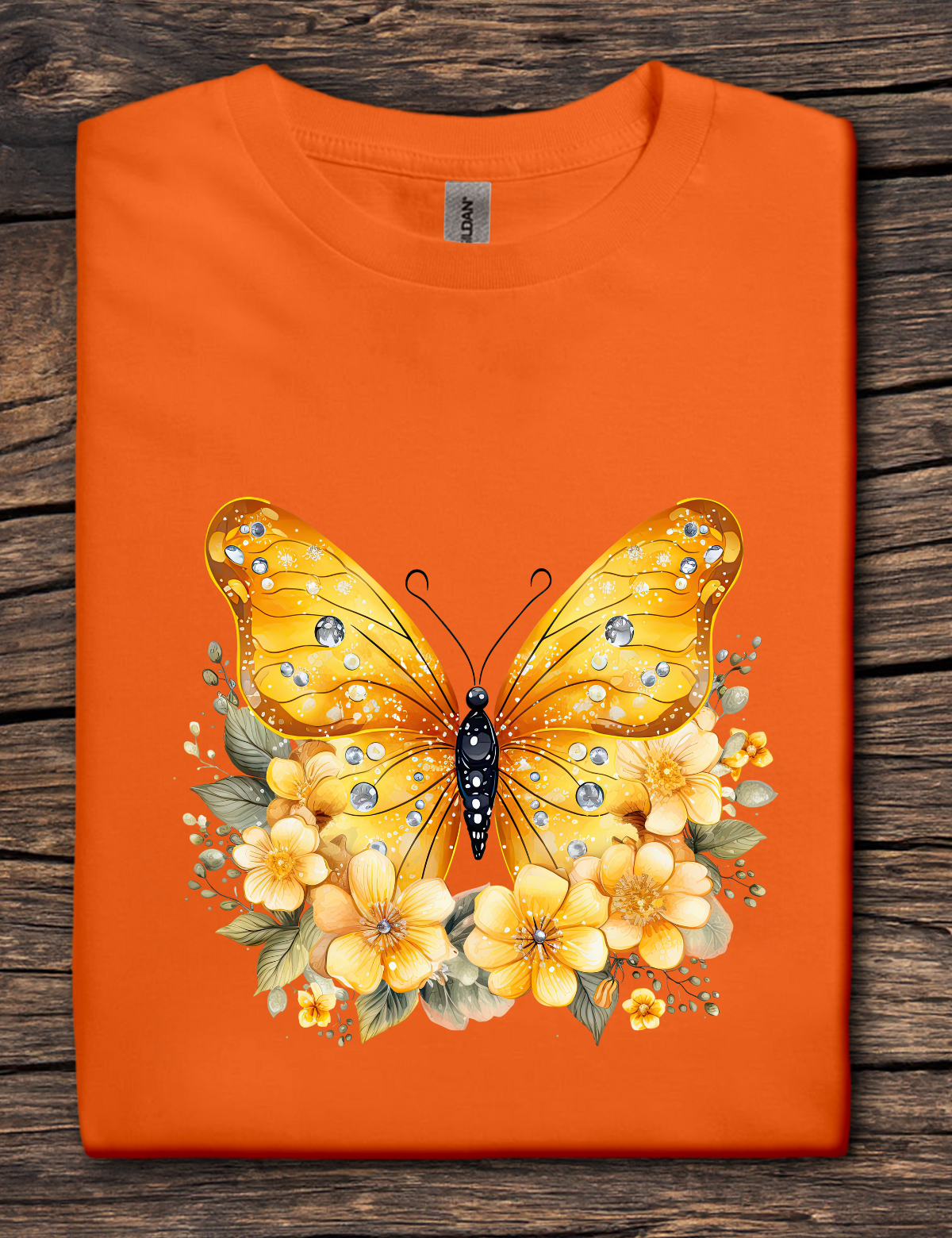 Orange t-shirt with a yellow butterfly and floral design on a wooden surface
