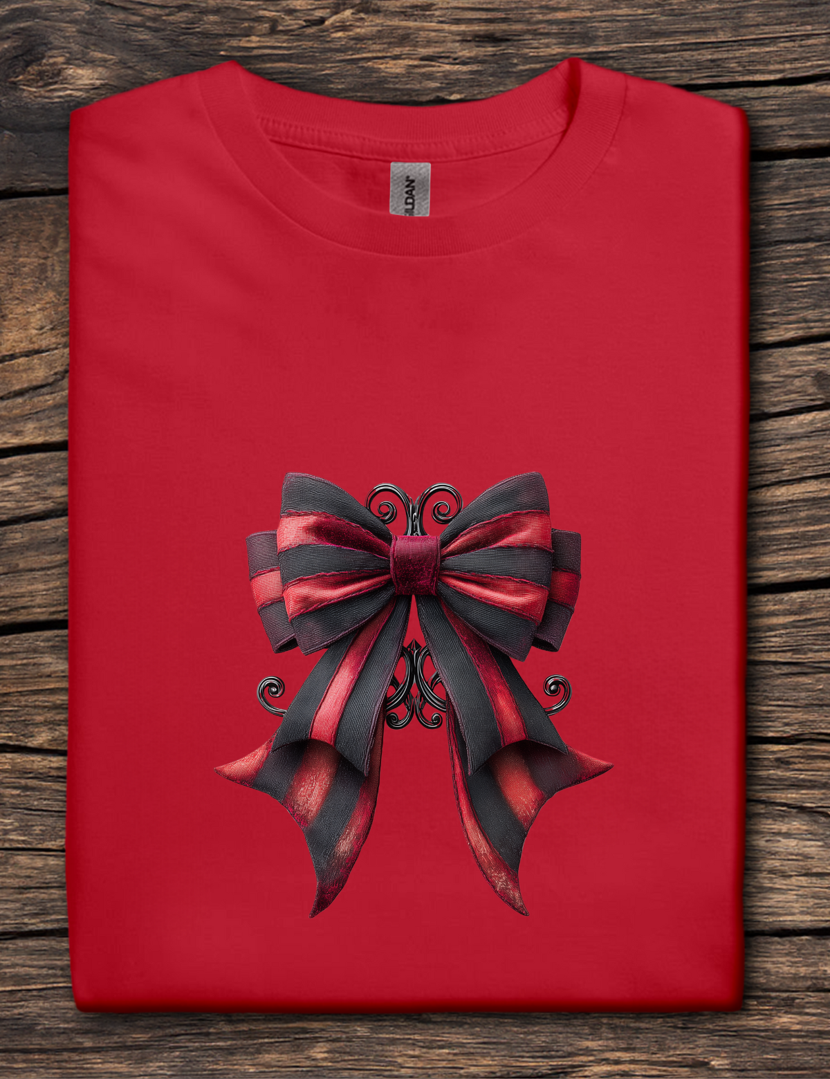 Red t-shirt with a large black and red bow design on a wooden surface