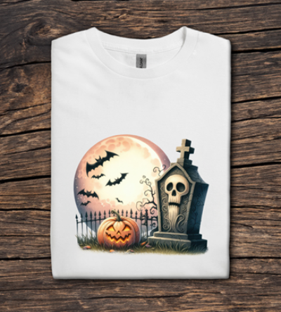 White t-shirt with Halloween design featuring a pumpkin, tombstone, and moon on a wooden surface