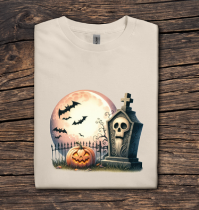 Folded t-shirt with Halloween design featuring a pumpkin, tombstone, and moon on a wooden surface