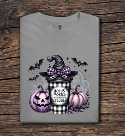 Gray t-shirt with Halloween-themed design featuring a witch hat, pumpkins, and a cup on a wooden surface.