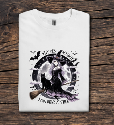 White t-shirt with witch graphic and text on a wooden surface