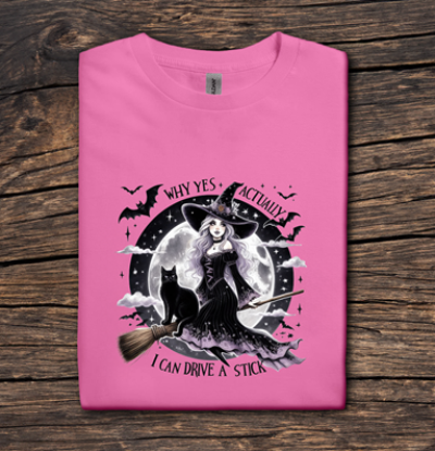 Pink t-shirt with a witch graphic on a wooden surface