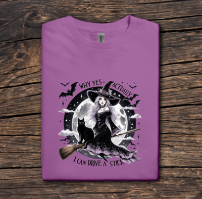 Purple t-shirt with a witch graphic and text on a wooden surface