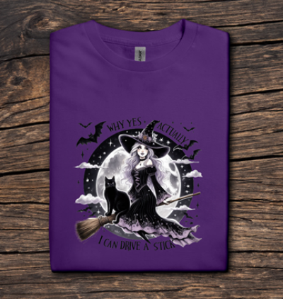 Purple t-shirt with a witch graphic on a wooden surface