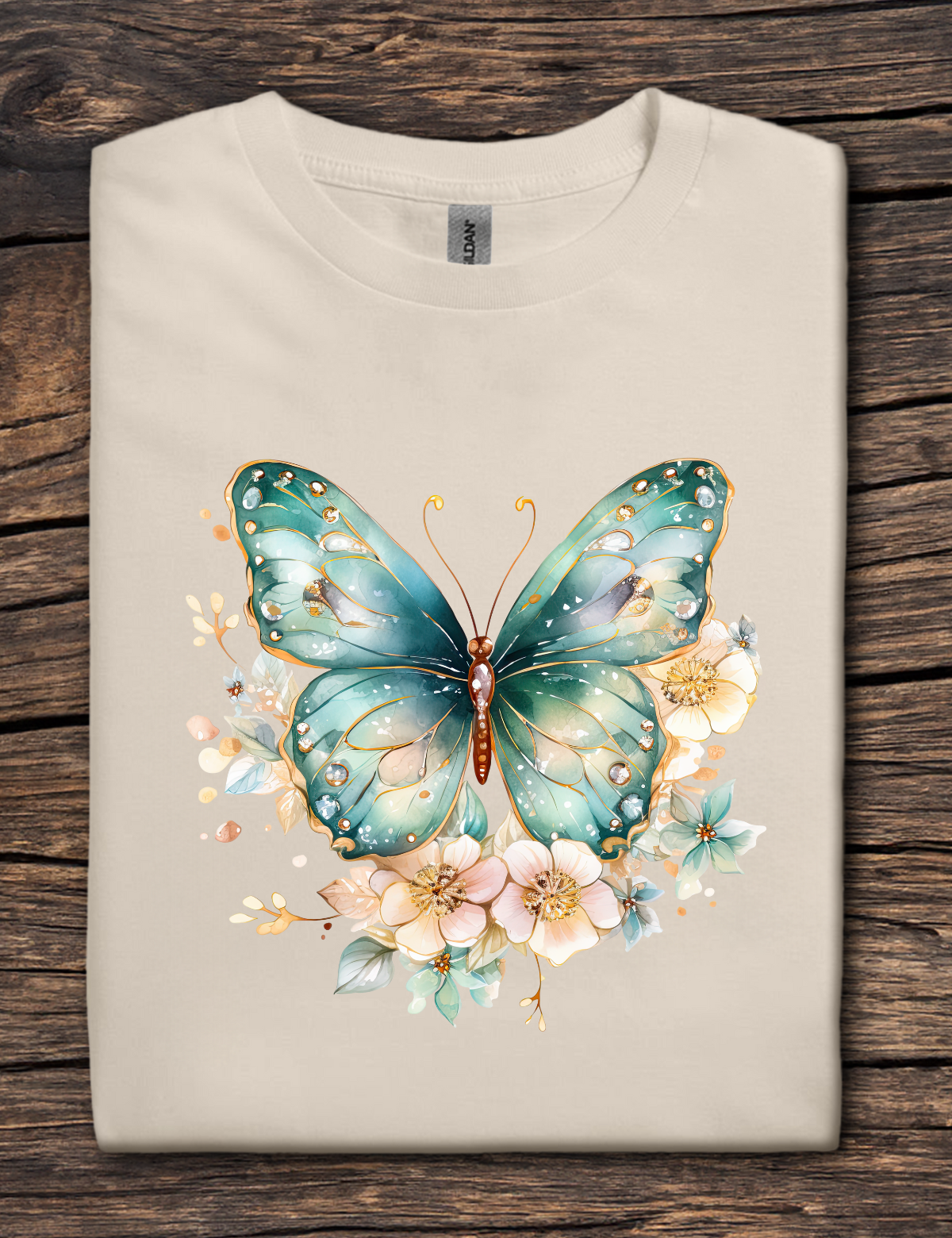 Beige t-shirt with a teal butterfly and floral design on a wooden surface